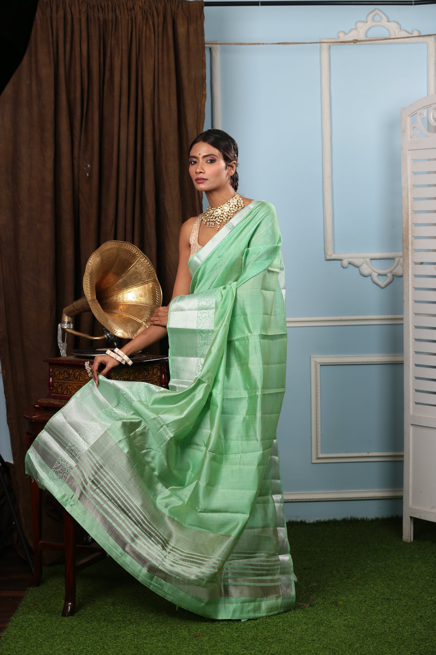 Model in a green raw silk saree with a silver border, suitable for temple wear. | Urbane Essence