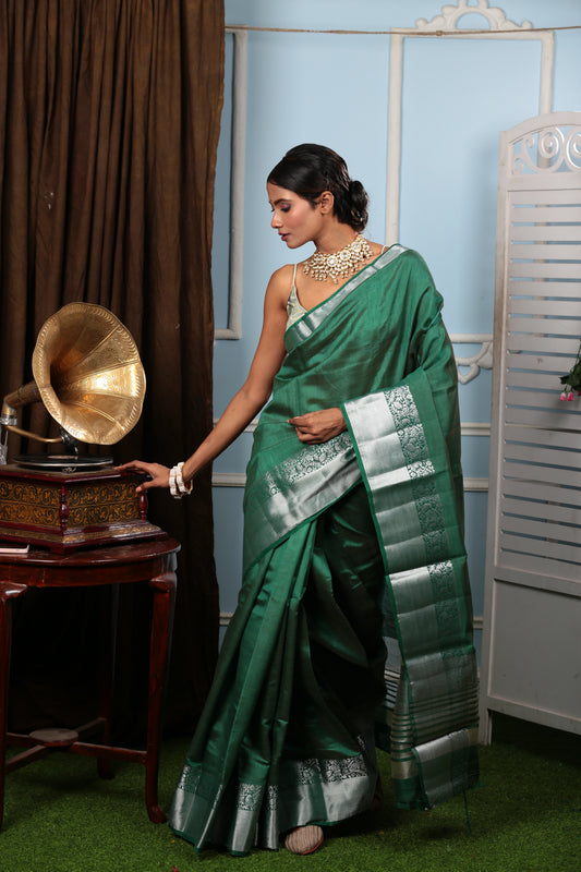 Woman in a green raw silk saree with silver borders, suitable for temple wear. | Urbane Essence