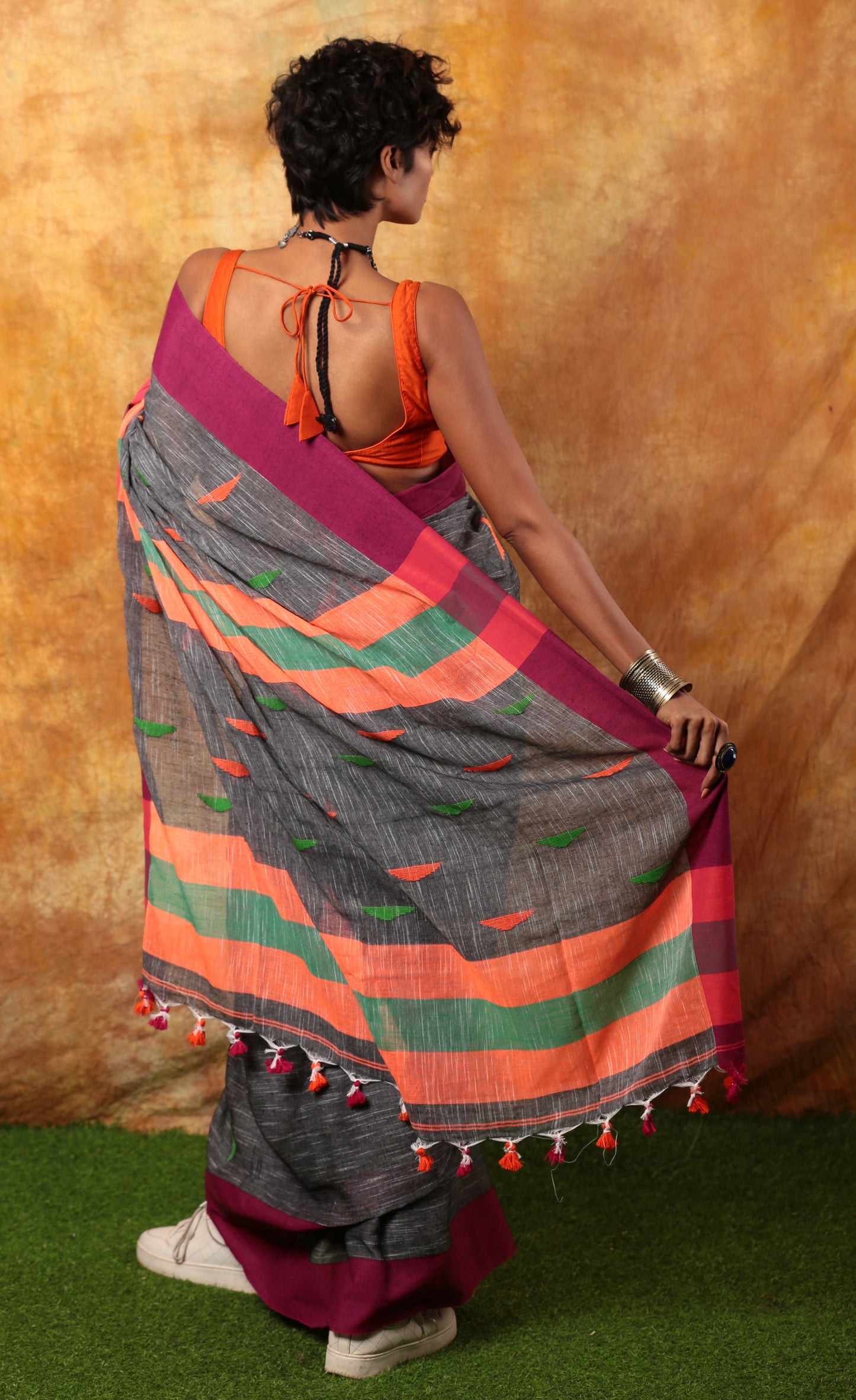 Woman in grey Assam Khadi saree with magenta and orange borders, green accents, and tassels, ideal for work | Urbane Essence