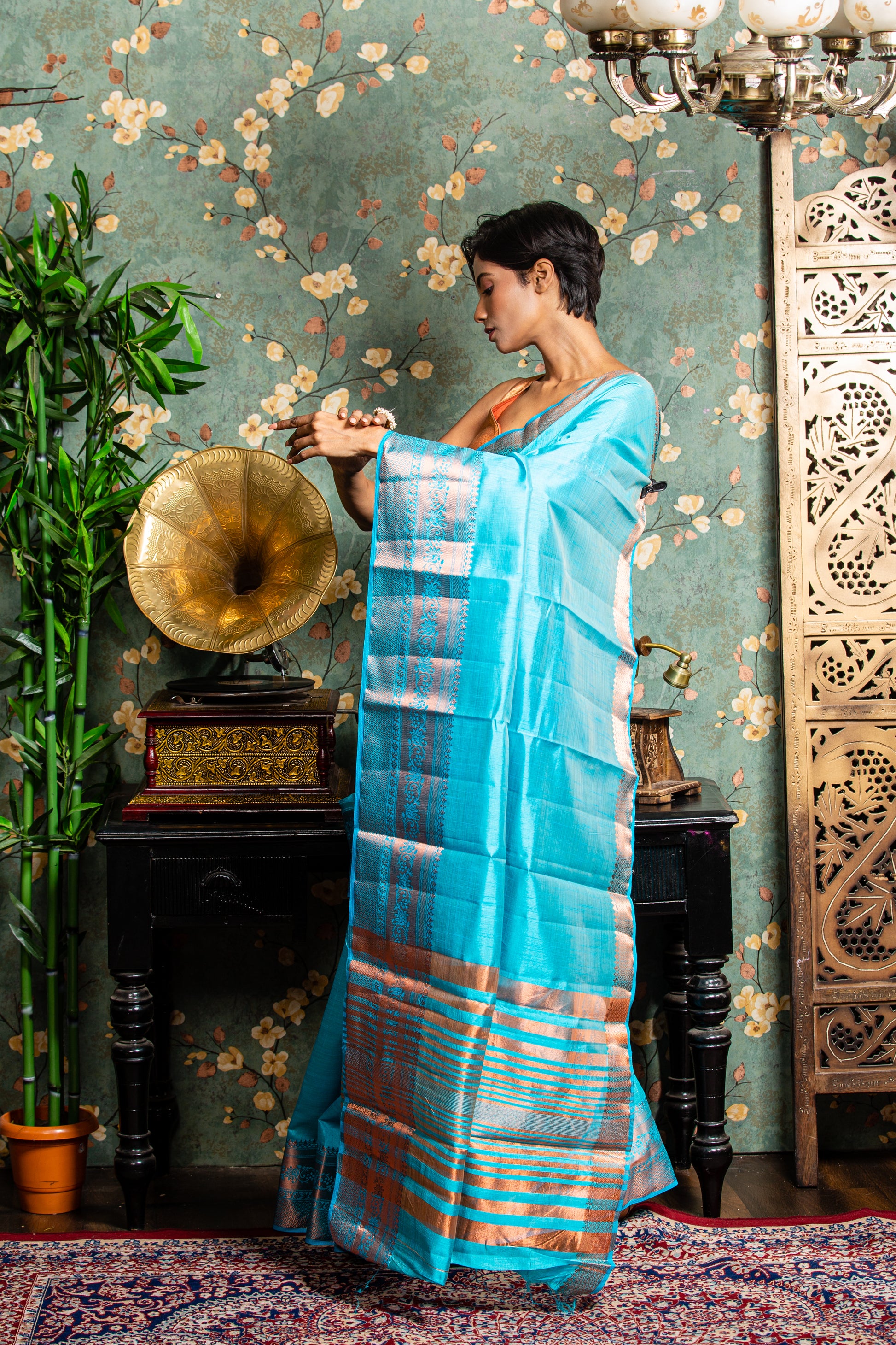 Woman in a baby blue raw silk saree with copper accents, ideal for festive occasions. | Urbane Essence