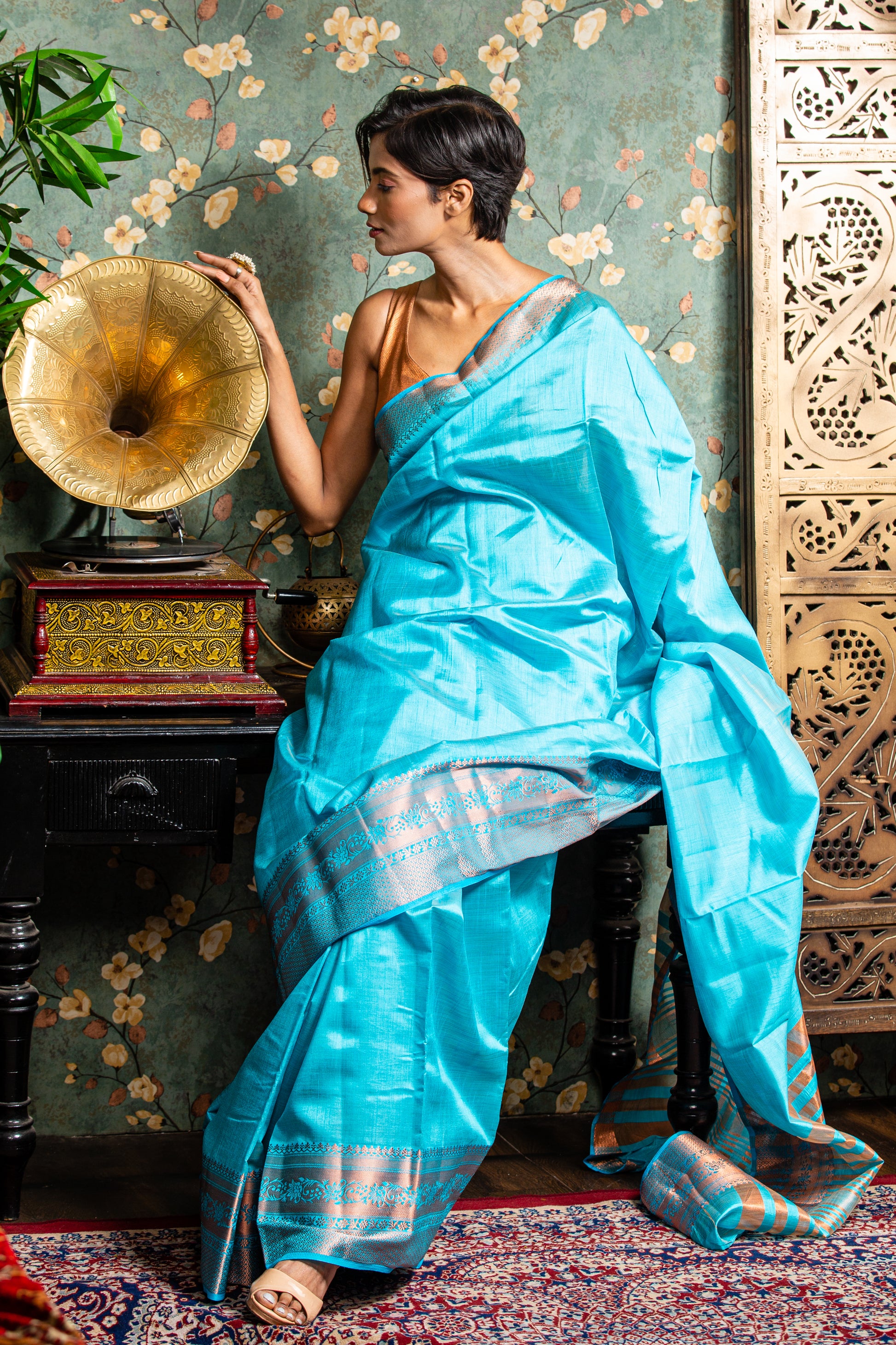 Woman in a baby blue raw silk saree with copper accents, ideal for festive occasions. | Urbane Essence