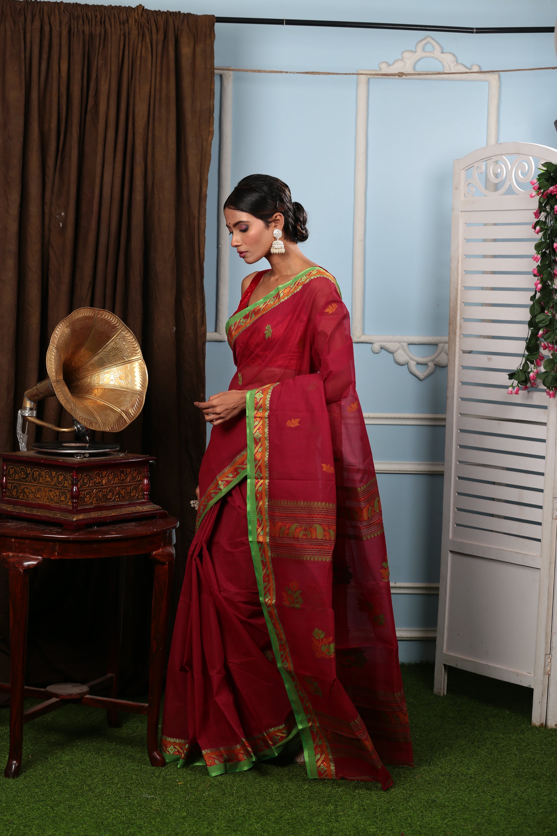 Elegant red Tant saree with green border, sparse patterns, and floral pallu, perfect for festive occasions. | Urbane Essence
