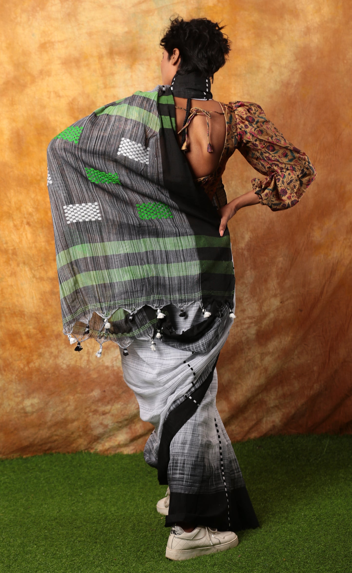 White and black Assam Khadi saree with traditional patterns, green accents, and tassels, ideal for summer mornings | Urbane Essence