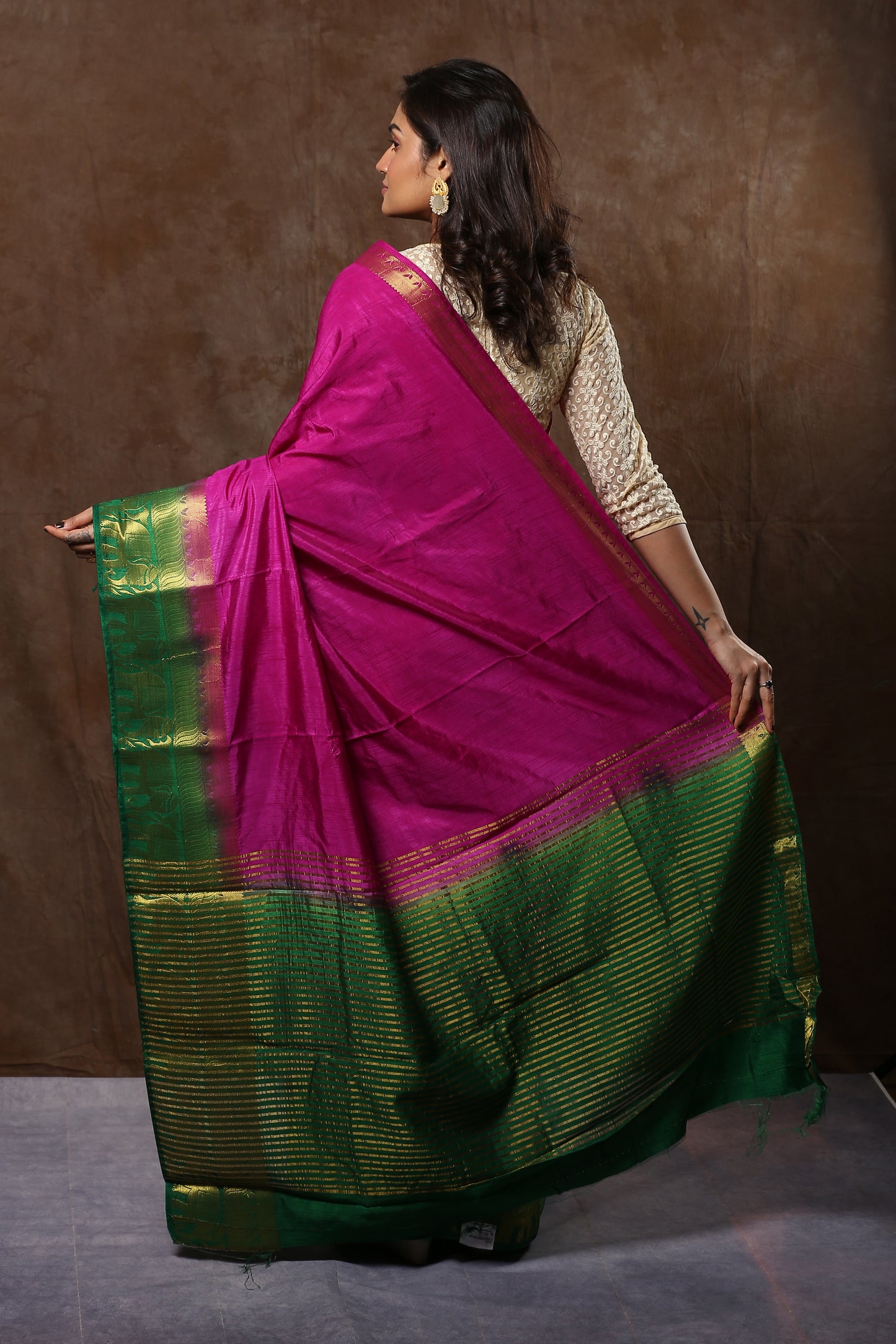 Sun-kissed Rosewood raw silk saree with broad green border, golden zari patterns, traditional occasion wear | Urbane Essence