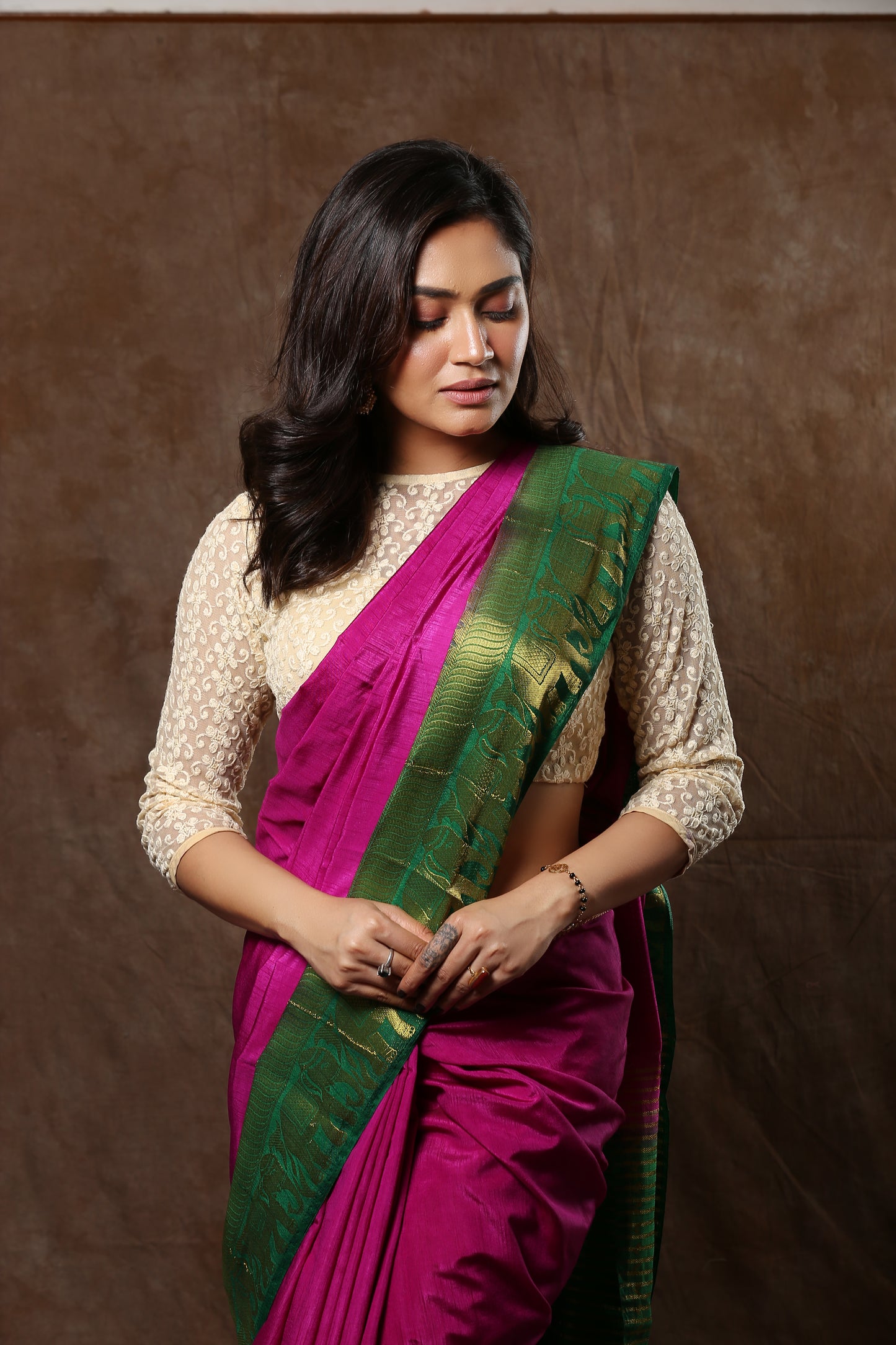 Sun-kissed rosewood raw silk saree with broad green border and golden zari patterns, perfect for traditional occasions | Urbane Essence