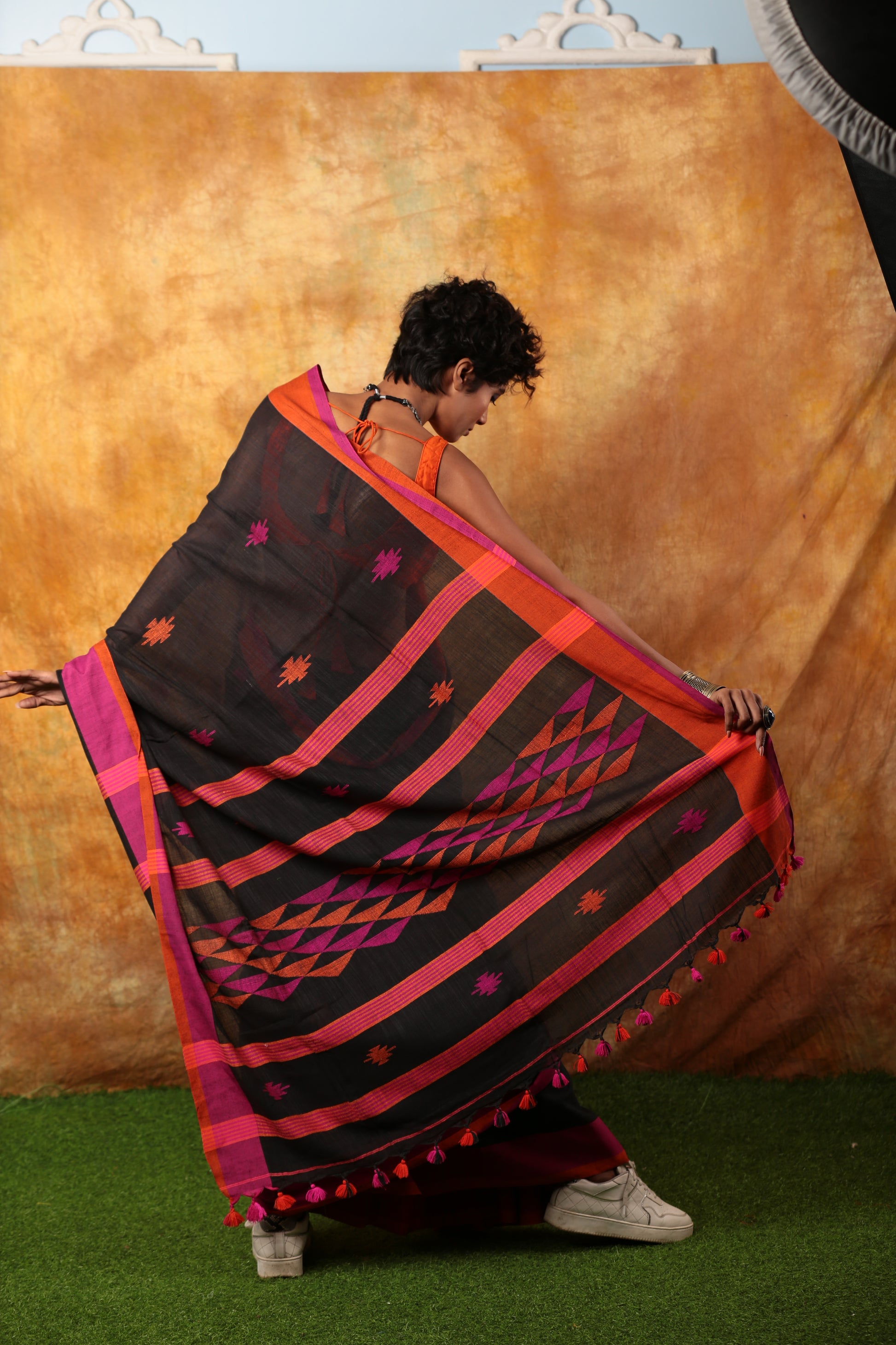 Black Assam Khadi saree with pink and orange borders, geometric patterns, and tassels, perfect for festive occasions | Urbane Essence